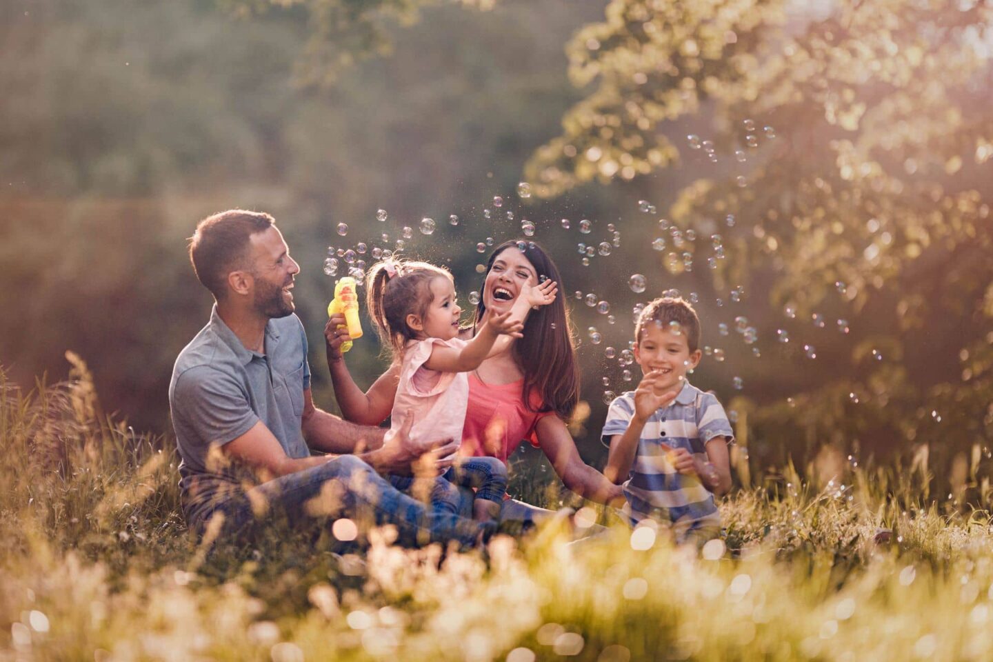 Family blowing bubbles in a field