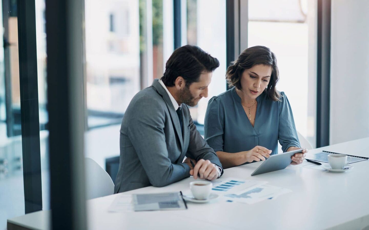 Woman helping man understand something on a tablet computer