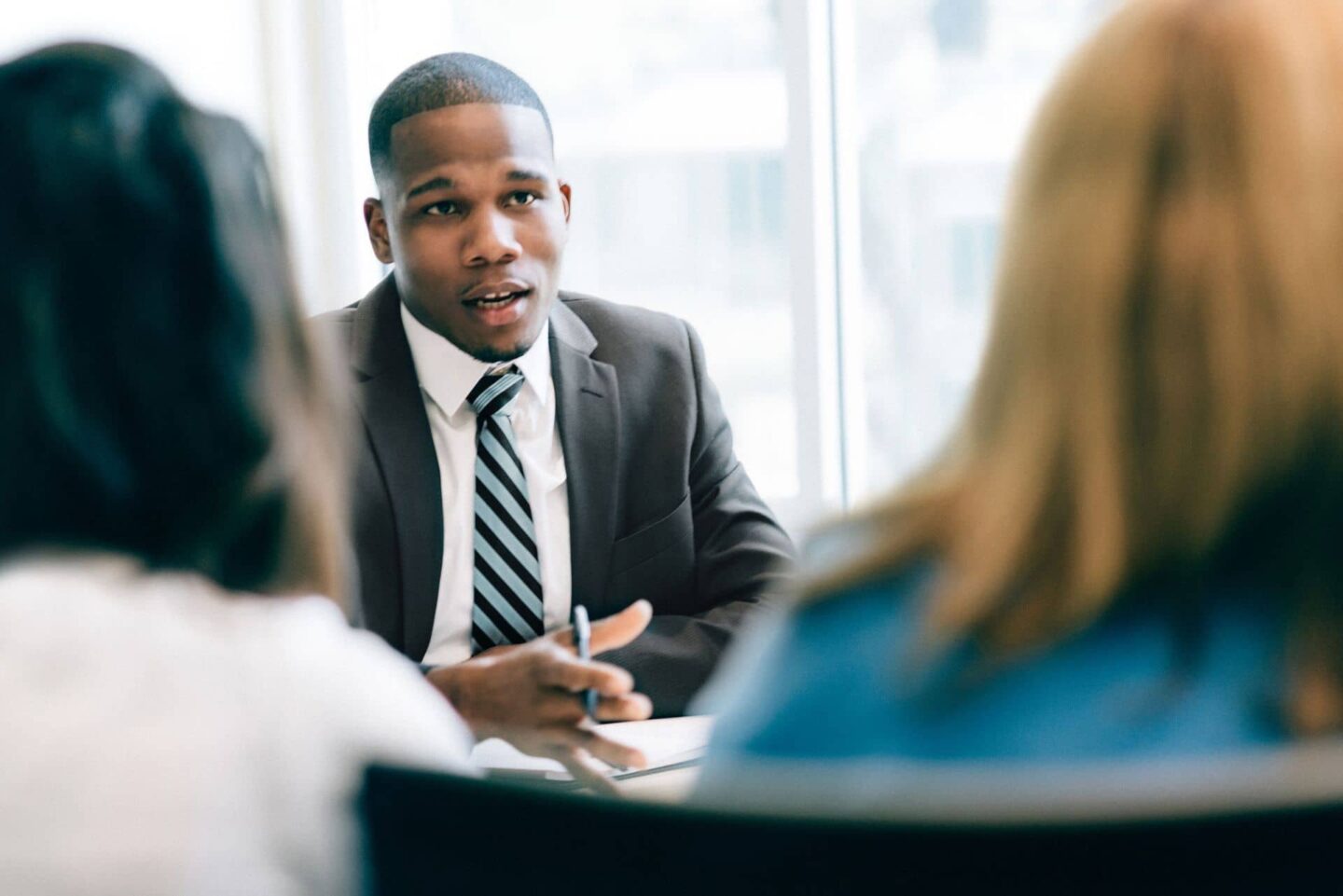 Man in suit talking to two people