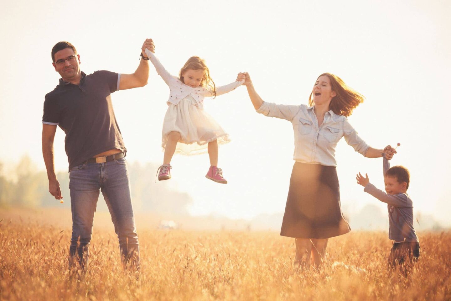 Young child being thrown by parents in a field